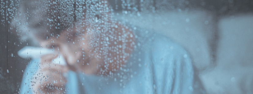 Elder woman crying looking through rainy window