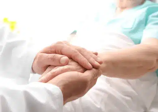 A doctor holding an elderly patient's hand