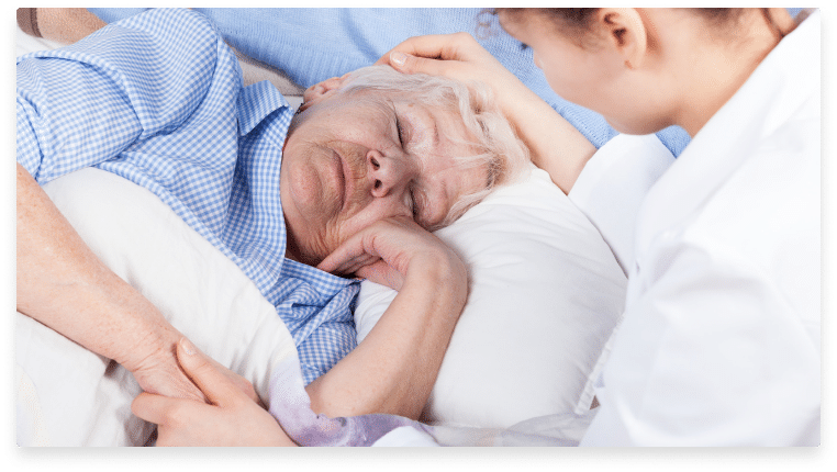 A nurse looking at a stage 3 bedsore elderly woman lying on a bed