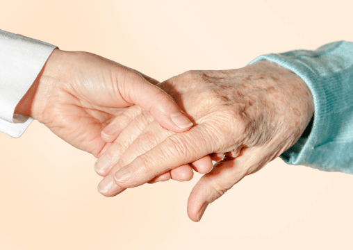 A nurse holding the hand of a bedsore patient.