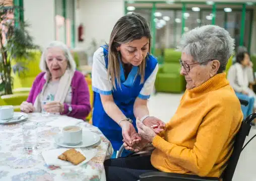 Nurse giving medication to elderly woman in wheelchair