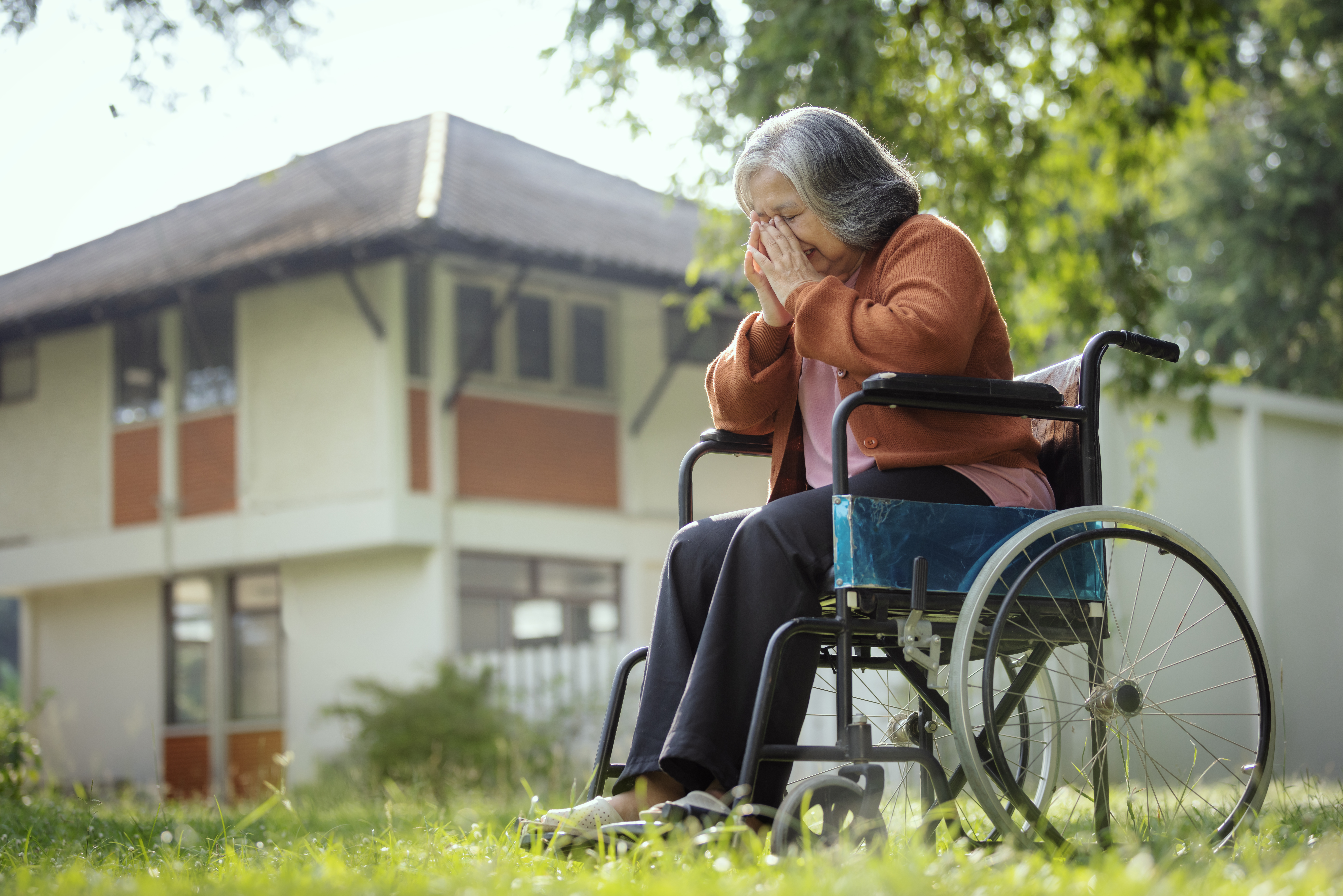 Senior woman sitting on wheelchair and recovering staring at something with a feeling of loneliness near the nursing home.