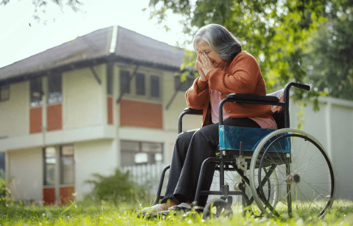 Senior woman sitting on wheelchair and recovering staring at something with a feeling of loneliness near the nursing home.